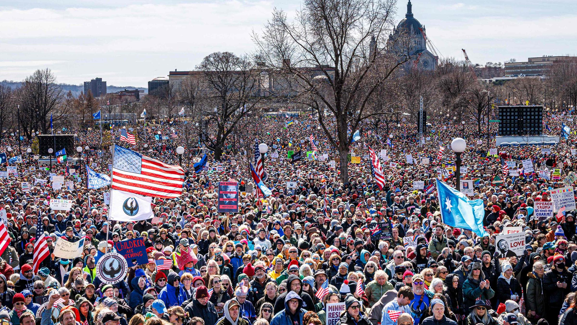 Menschen halten Fahnen und Schilder, als sich am 28. März 2026 in Saint Paul, Minnesota, im Rahmen des nationalen Protesttages „No Kings“ eine große Menschenmenge vor dem Minnesota State Capitol versammelt.