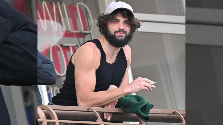 Noah Centineo wie er in die Kamera schaut und lächelt.