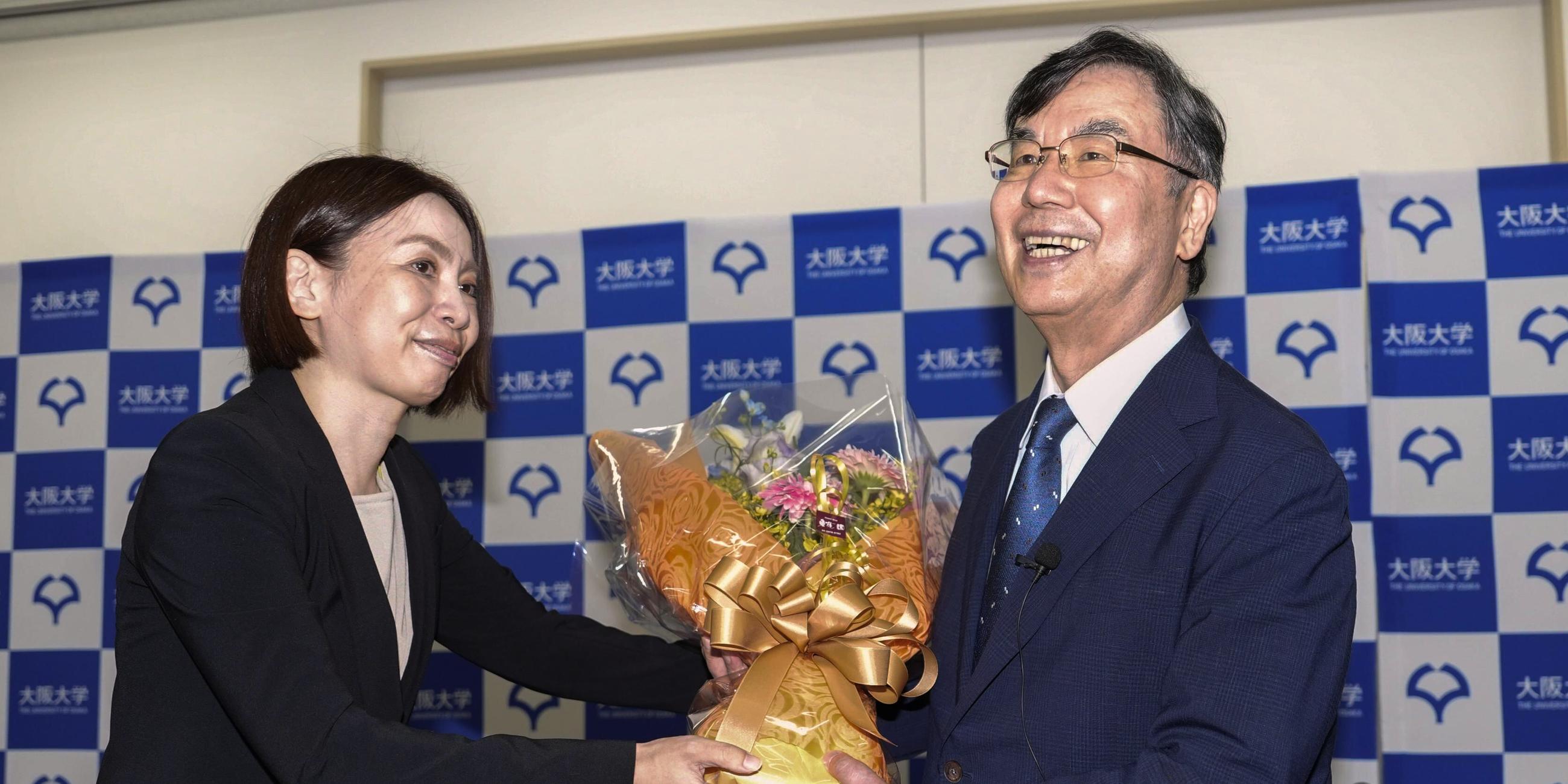 Shimon Sakaguchi (r), Professor an der Universität Osaka, erhält bei einer Pressekonferenz in Suita Blumen, nachdem er den Nobelpreis für Medizin erhalten hat. 