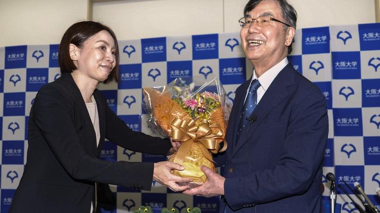 Shimon Sakaguchi (r), Professor an der Universität Osaka, erhält bei einer Pressekonferenz in Suita Blumen, nachdem er den Nobelpreis für Medizin erhalten hat. 