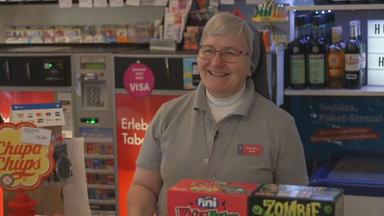 Birgit Baier im "Büdchen" in Gelsenkirchen. Im Innenraum reihen sich bunte Kühlschränke mit Bier und Softdrinks an Regale mit Zigaretten, Instant-Nudeln und Proteinriegeln. 
