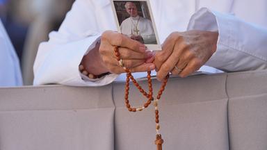 Eine Nonne hält ein Bild von Papst Leo XIV. und einen Rosenkranz.