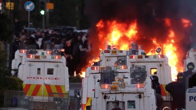 Die Polizei versucht, Demonstranten zu zerstreuen, während in der Nähe von Newtownabbey bei Belfast (Nordirland) ein Feuer brennt.