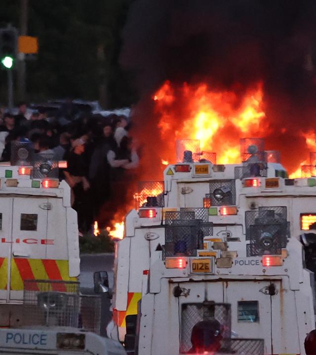 Die Polizei versucht, Demonstranten zu zerstreuen, während in der Nähe von Newtownabbey bei Belfast (Nordirland) ein Feuer brennt.
