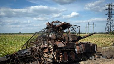 Ein zerstörter russischer Panzer liegt am Straßenrand.