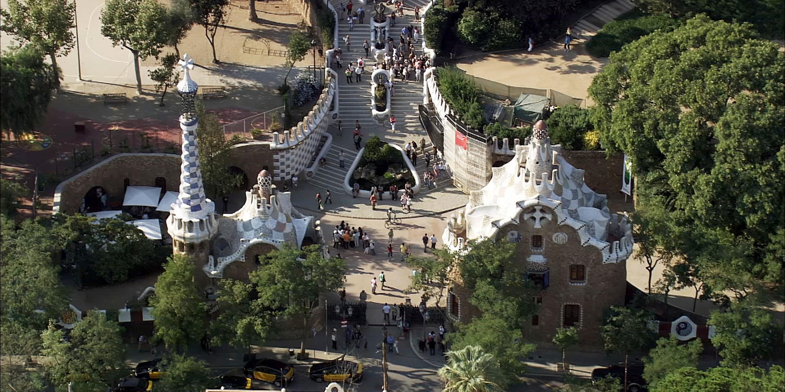 Bauten von Antonio Gaudi: eine elegante Treppe zwischen Bäumen und reich verzierten Gebäuden in Barcelona im Park Güell.