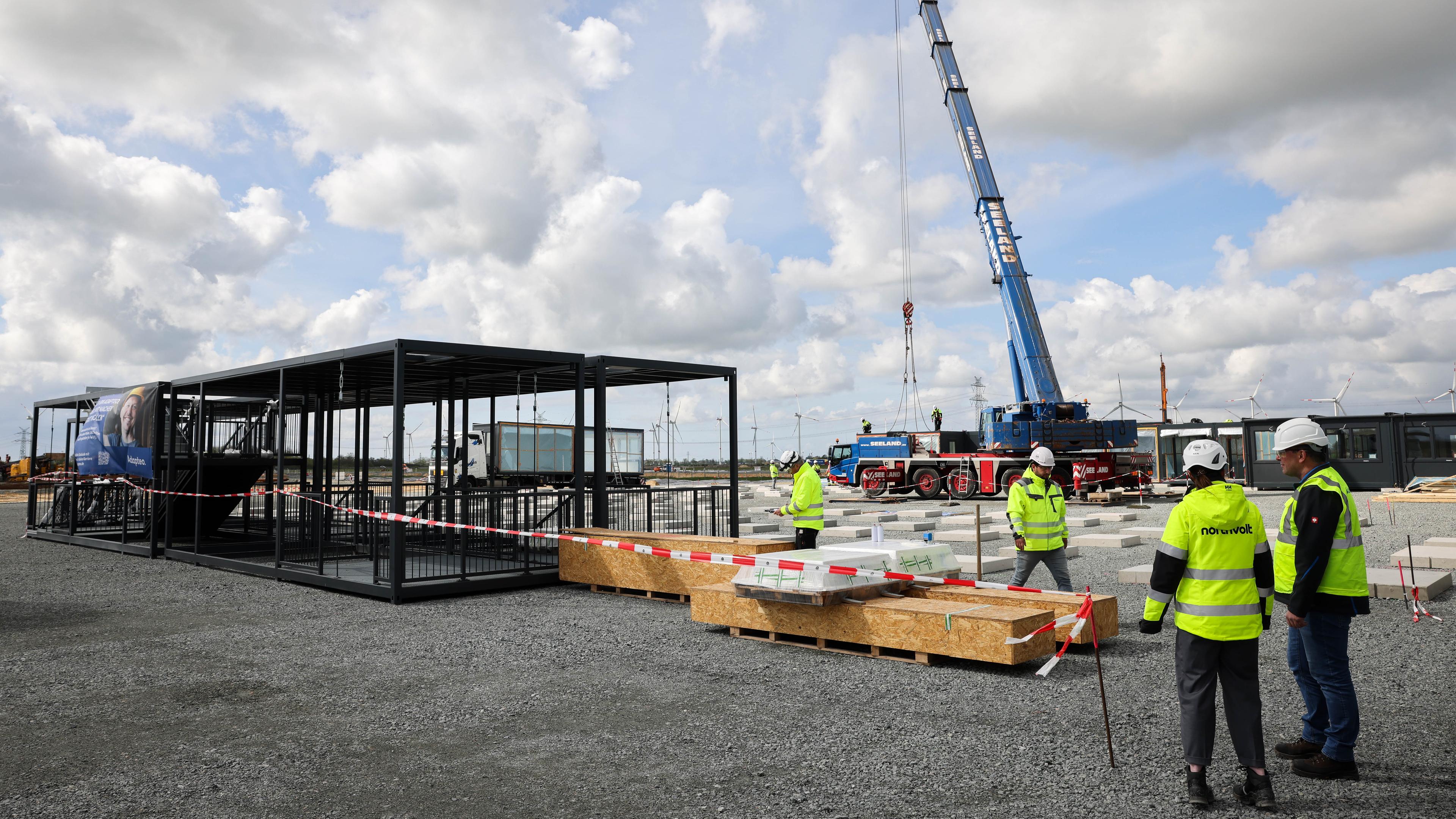 Ein Autokrahn hebt Teile einer temporären Modulanlage für ein Bürogebäude auf dem Ersten Baufeld der Baustelle der Northvolt Drei Gigafactory