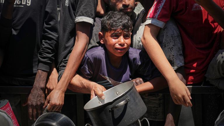 Palästinenser kämpfen am Freitag, den 23. Mai 2025, um das in einer Gemeinschaftsküche im Stadtteil Muwasi von Khan Younis im Gazastreifen verteilte warme Essen. 