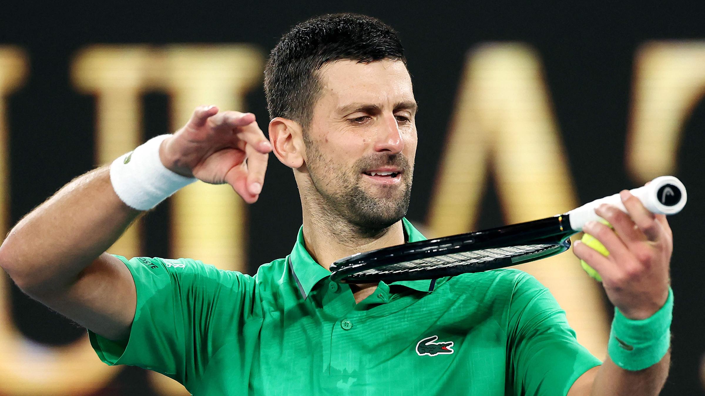 Novak Djokovic ahmt das Geigenspiel auf seinem Schläger nach, als er seinen Sieg über Botic van de Zandschulp in Melbourne am 24. Januar 2026 feiert.