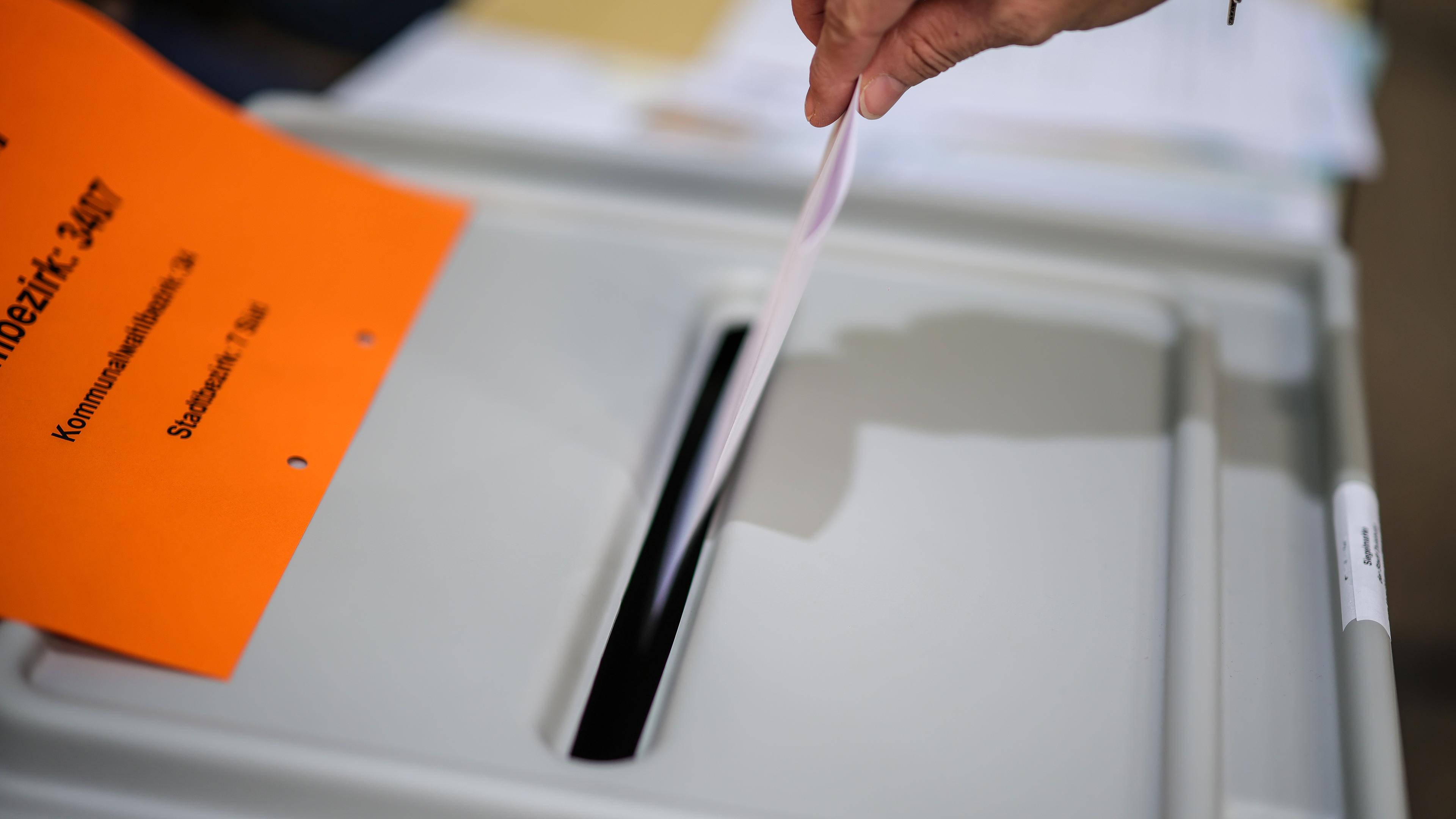 Kommunalwahl typical 1 - man sieht wie ein Zettel in eine Wahrurne eingeworfen wird