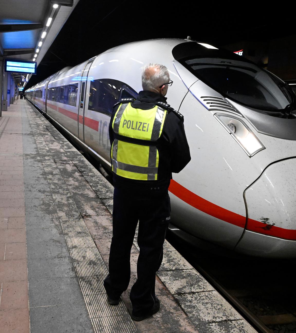 Ein Polizist steht auf einem Bahnsteig im Bahnhof Siegburg, auf dem ein ICE der Deutschen Bahn steht.