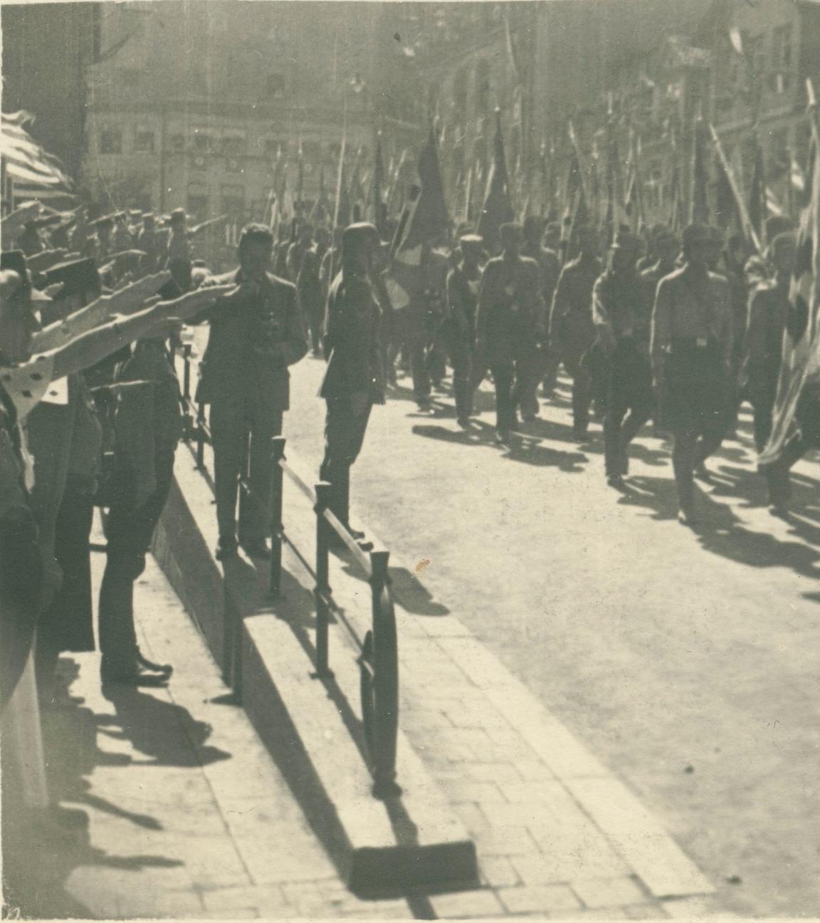 Der Reichsparteitag der NSDAP in Nürnberg im Jahr 1934. Soldaten marschieren durch die Straßen und halten Fahnen.