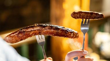 Bayern, Nürnberg: Eine Nürberger Bratwurst (r) und eine Thüringer Bratwurst, aufgespießt auf einer Gabel