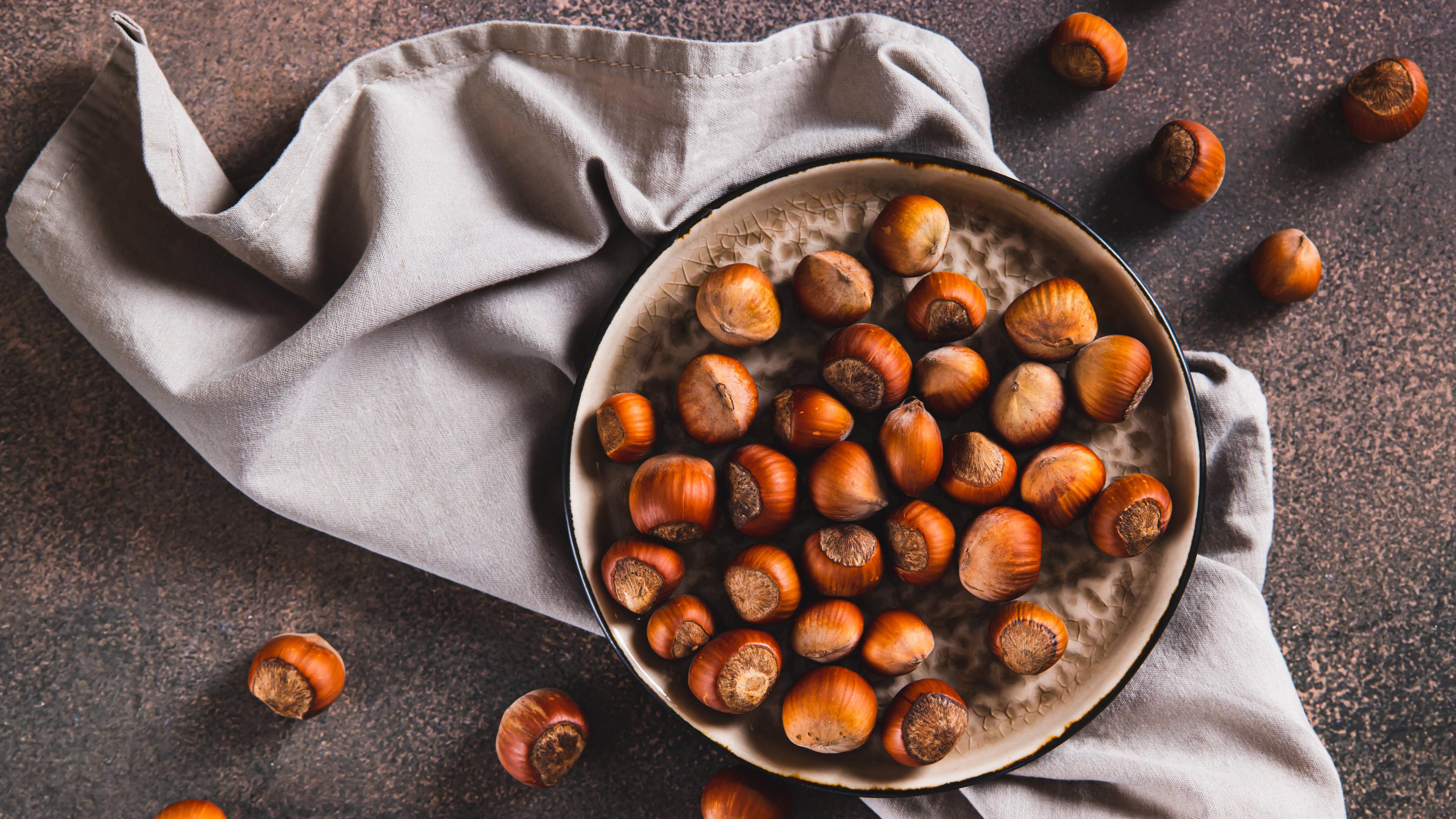 Haselnüsse liegen in einer Schale und daneben.