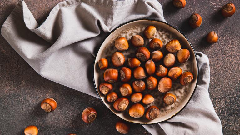 Haselnüsse liegen in einer Schale und daneben.