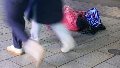 Ein Wohnungsloser liegt in eine Jacke gehüllt in einer Fußgängerzone während Passanten vorbeigehen am 27.10.2025 in Leipzig, Sachsen.