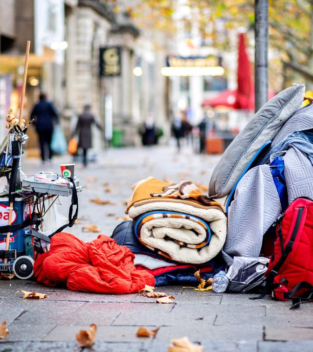 Die Habseligkeiten eines Obdachlosen liegen auf einem Bürgersteig in der Innenstadt.