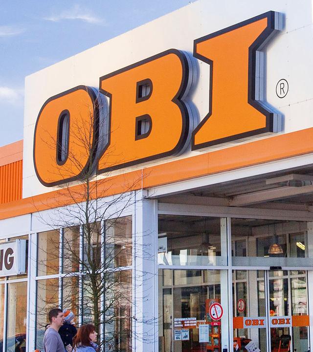 Pflanzen und Gartenzubehör stehen am Haupteingang eines Baummarkts von Obi.