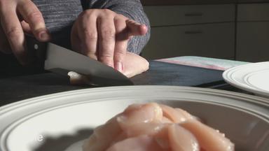Frau schneidet Hähnchenfleisch