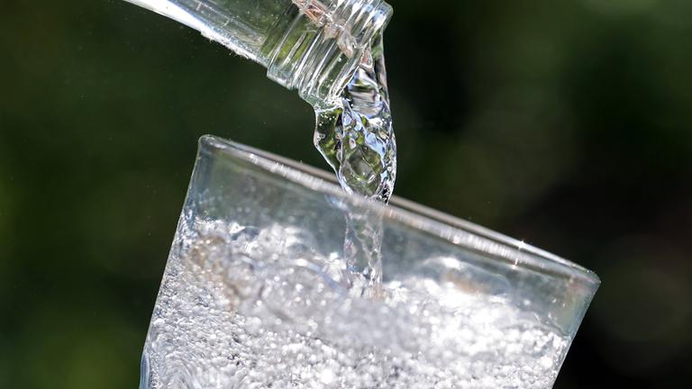 Mineralwasser wird aus einer Flasche in ein Glas gegossen.