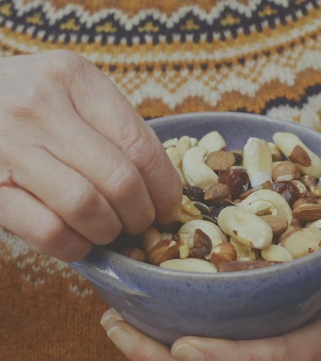 Jemand greift in eine Schale mit Studentenfutter