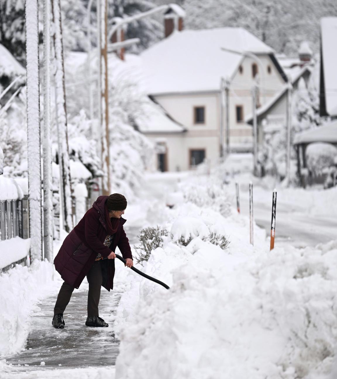 Eine Frau räumt Schnee im Bezirk St. Pölten-Land in Neulengbach, Österreich.