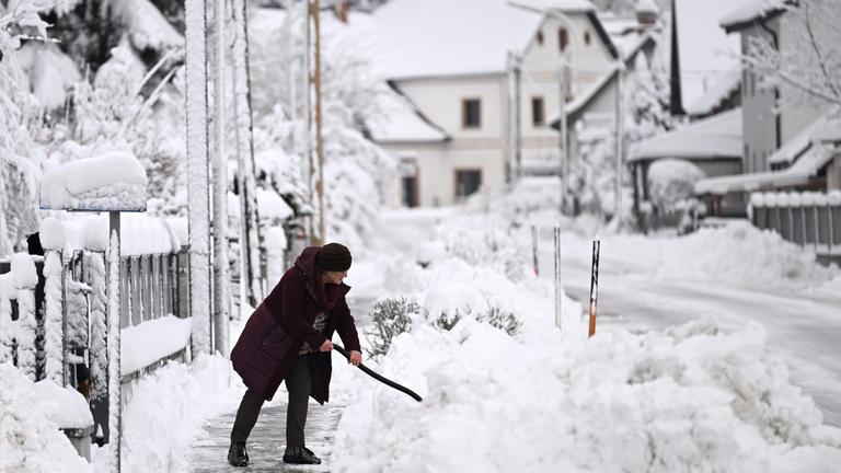 Eine Frau räumt Schnee im Bezirk St. Pölten-Land in Neulengbach, Österreich.