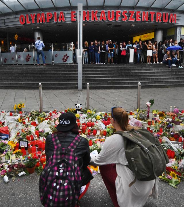 Blumen und Kerzen liegen vor dem Haupteingang des Olympia-Einkaufszentrums (OEZ).