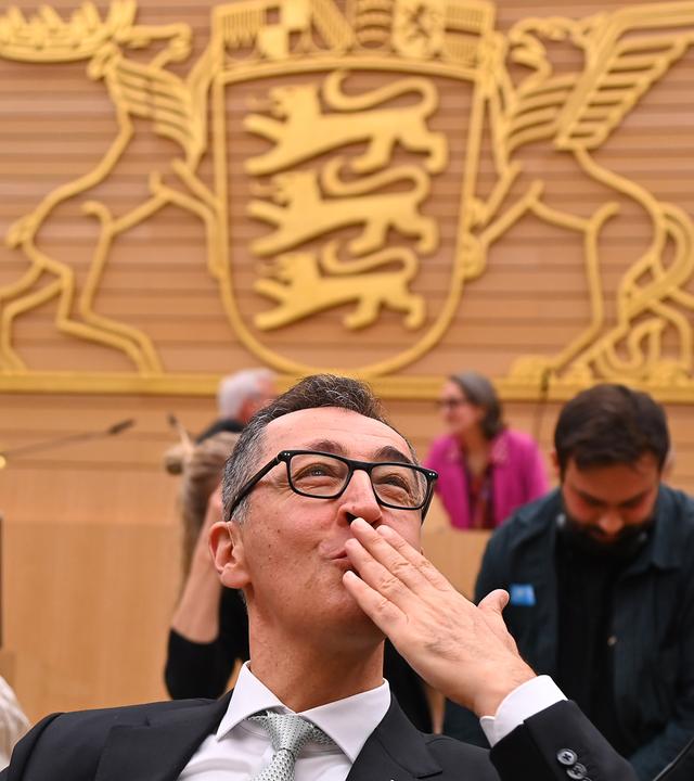 Cem Özdemir lächelnd und seine Hand küssend im Plenarsaal in Stuttgart.