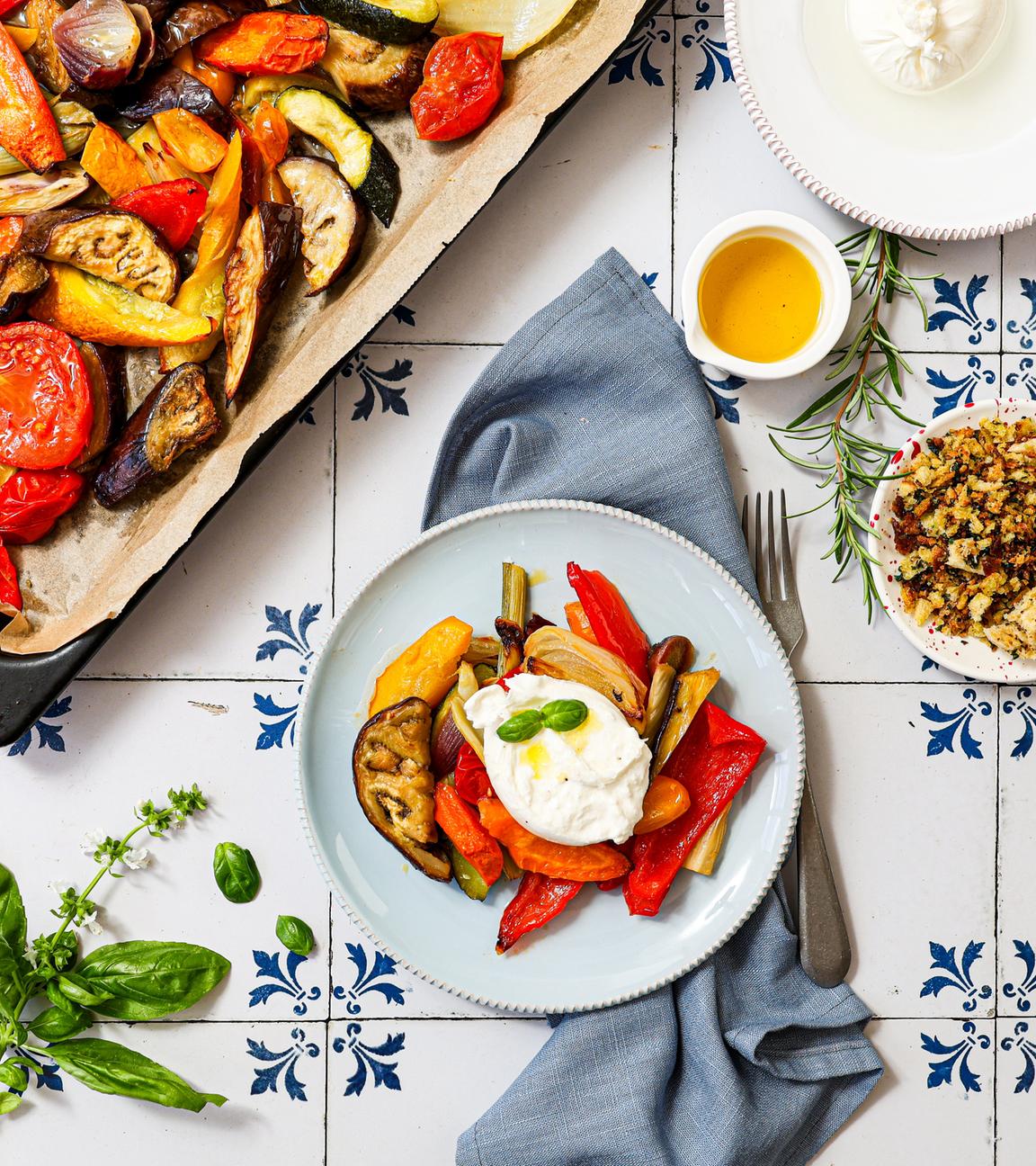 Ein Tisch mit einem Teller und Ofengemüse mit Burrata