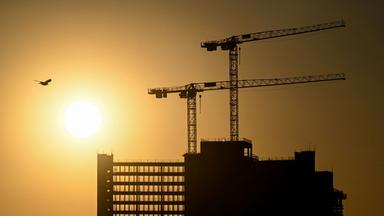Hinter einem im Bau befindlichen Gebäude geht die Sonne auf.