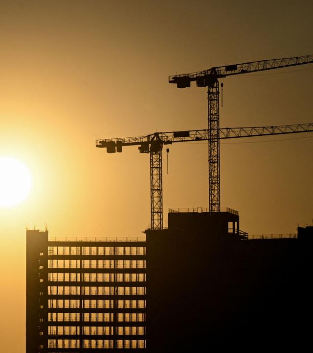 Hinter einem im Bau befindlichen Gebäude geht die Sonne auf.