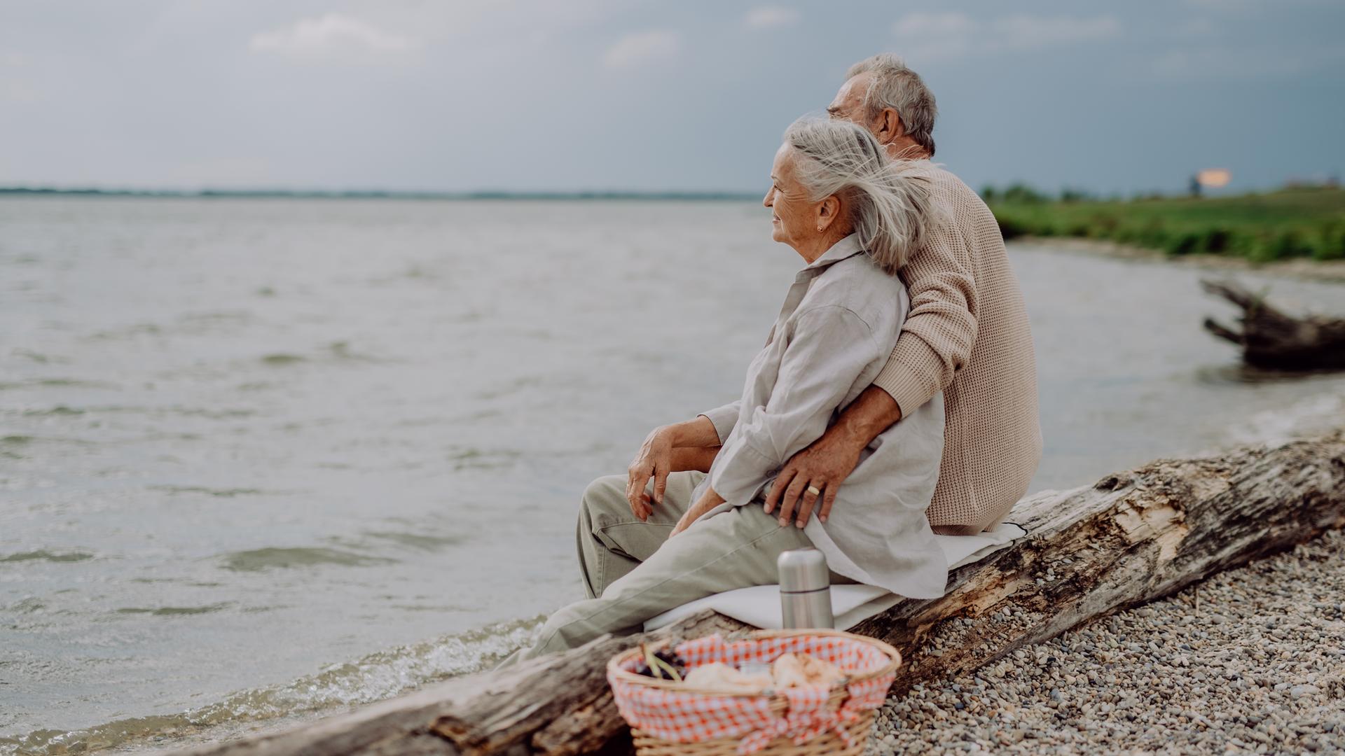 Älteres Paar macht ein Picknick am Meer im Herbst.