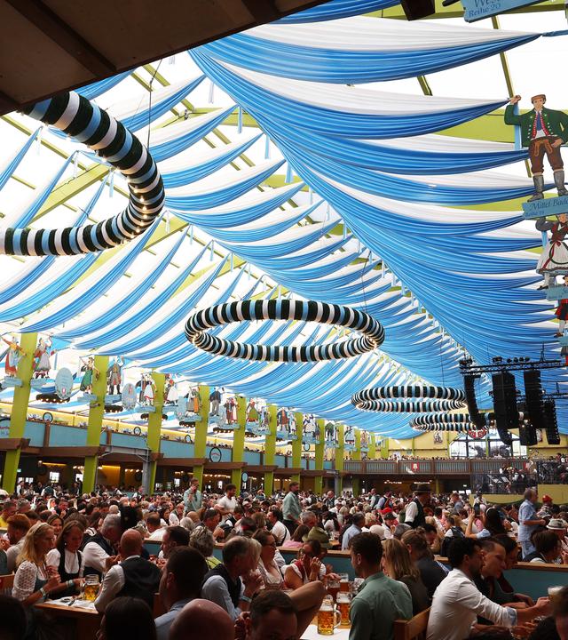 Im Innenraum eines Fetszeltes auf dem Münchner Oktoberfest 2026 sitzen viele Menschen.