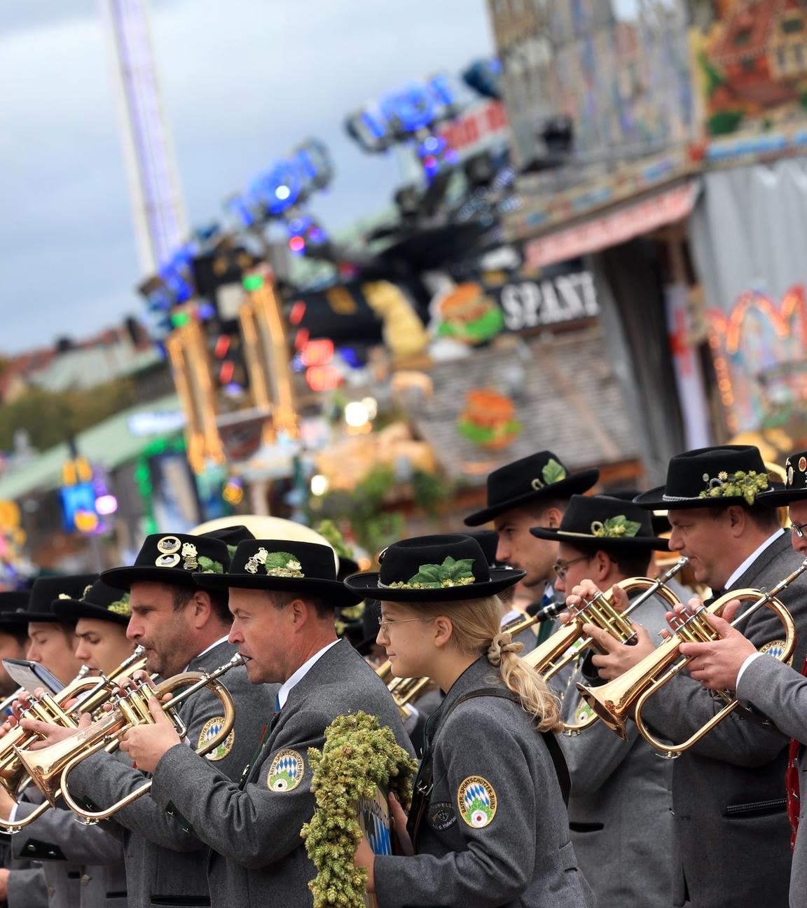 Bayerische Musikanten stehen am letzten Tag des Oktoberfestes unter bewölktem Himmel auf dem Festgelände.