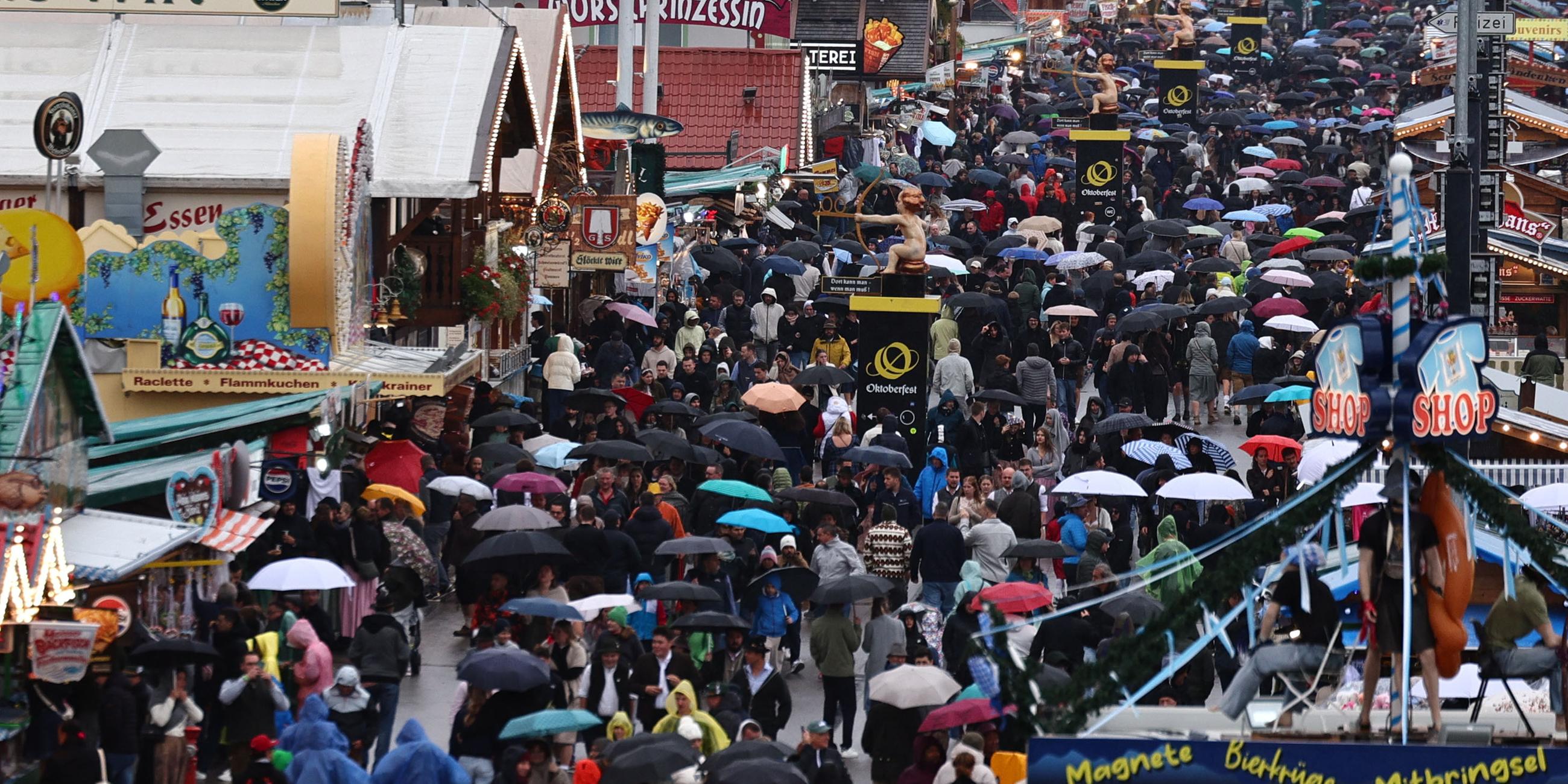Ganz viele Menschen auf der Wiesn, mit Regenschirmen