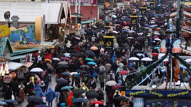 Ganz viele Menschen auf der Wiesn, mit Regenschirmen