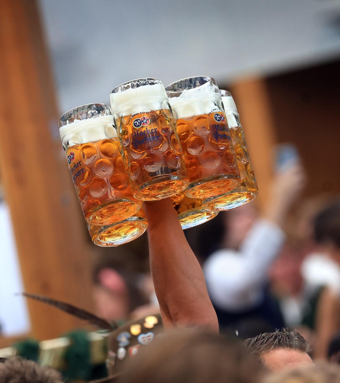 Eine Bedienung trägt in einem Festzelt auf dem Oktoberfest mehrere Maßkrüge.