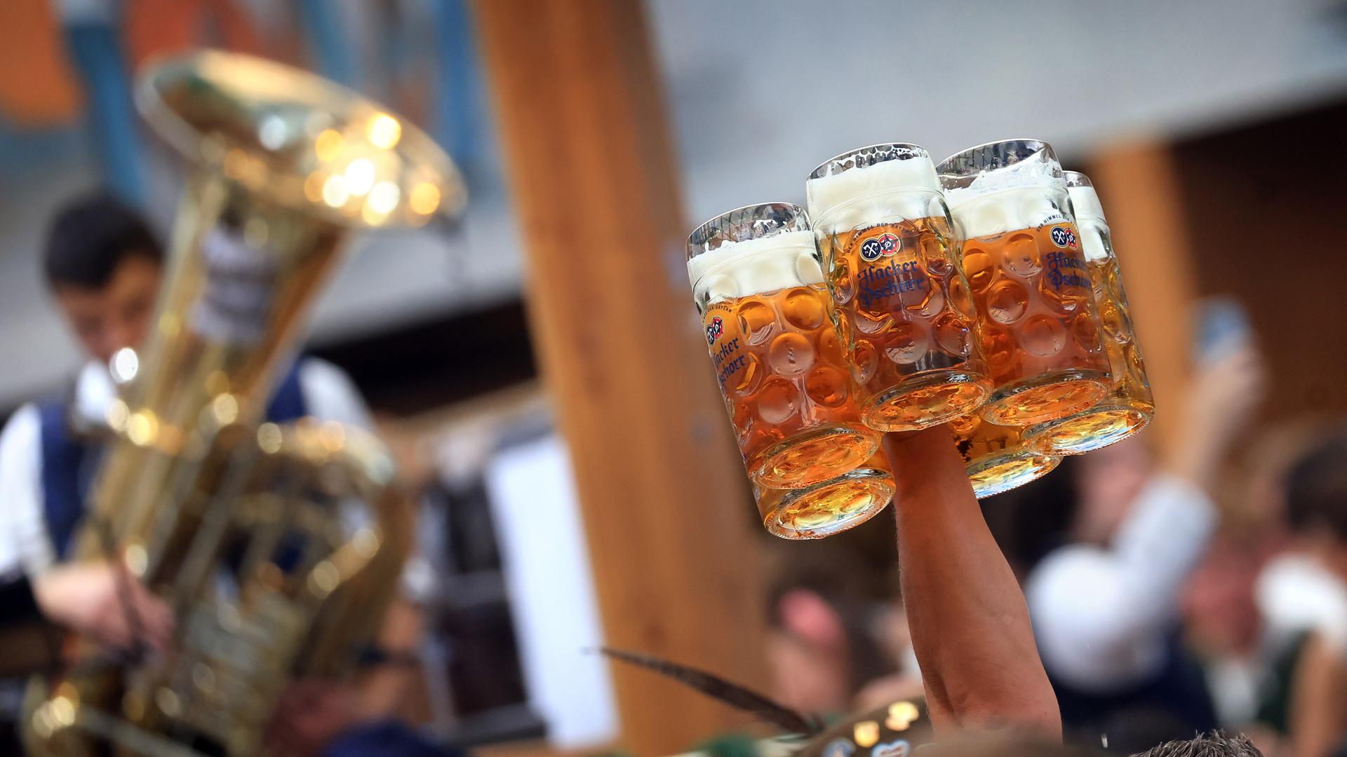 Eine Bedienung trägt in einem Festzelt auf dem Oktoberfest mehrere Maßkrüge.