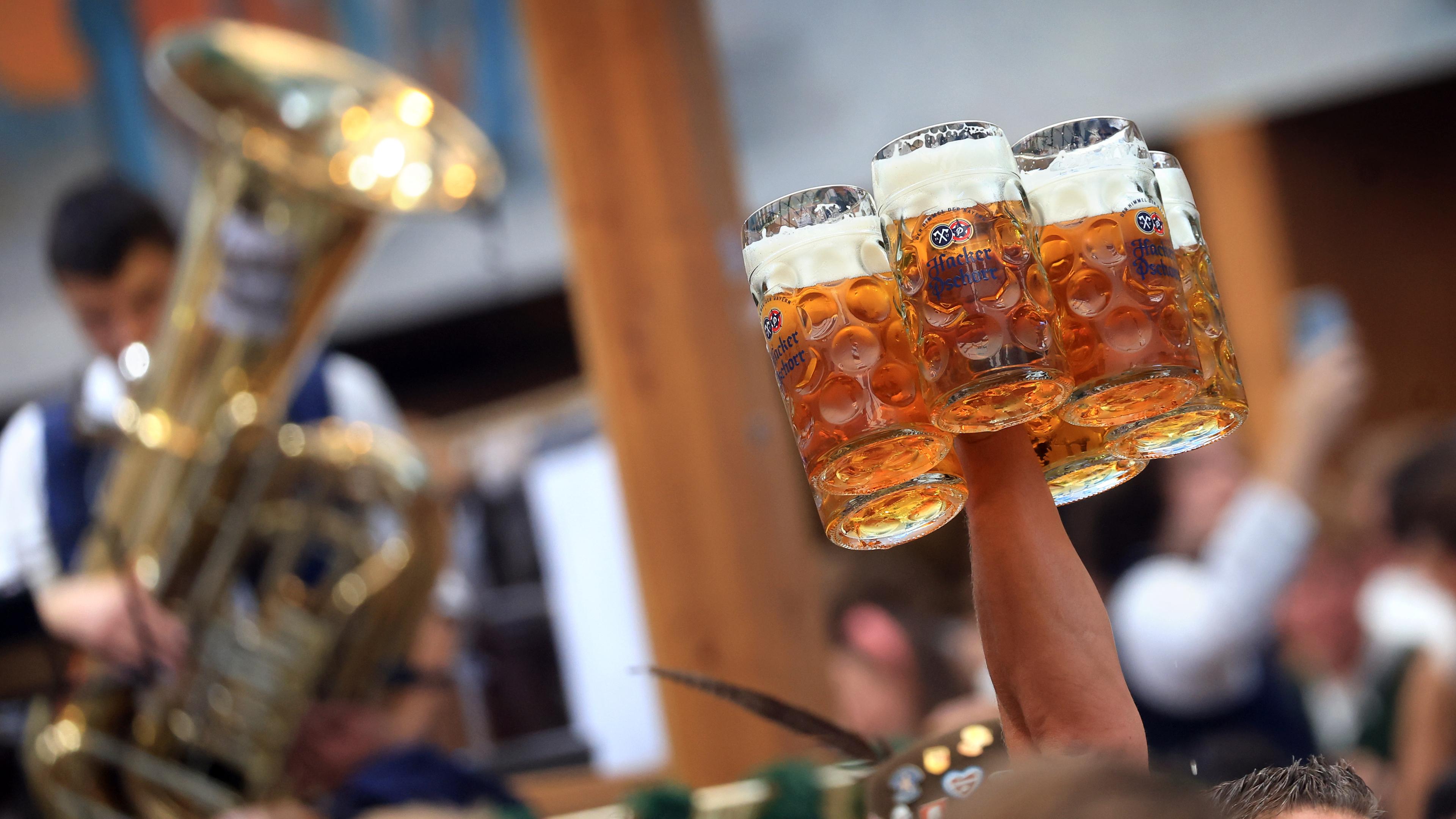 Eine Bedienung trägt in einem Festzelt auf dem Oktoberfest mehrere Maßkrüge.