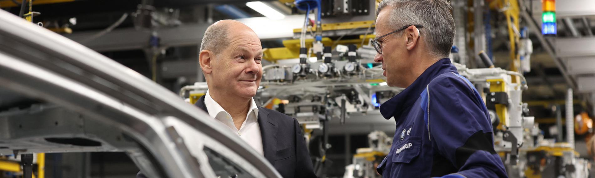 Olaf Scholz spricht mit BMW-Werksleiter Peter Weber während eines Besuchs des BMW-Werks in München, am 05.12.2023. 
