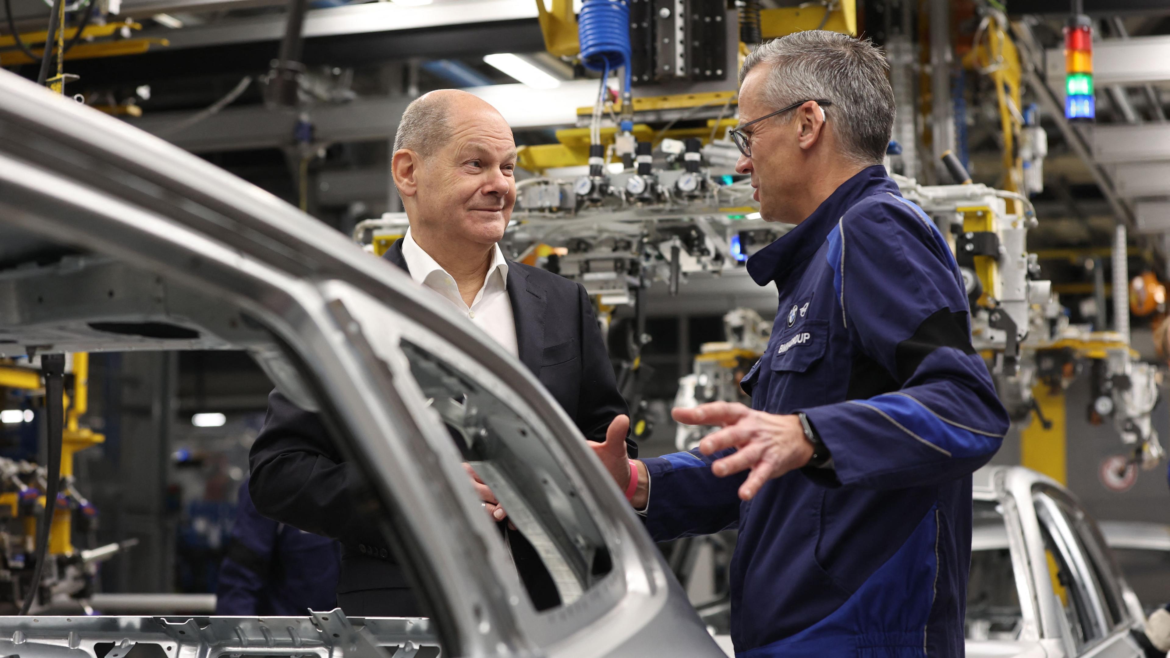 Olaf Scholz spricht mit BMW-Werksleiter Peter Weber während eines Besuchs des BMW-Werks in München, am 05.12.2023. 