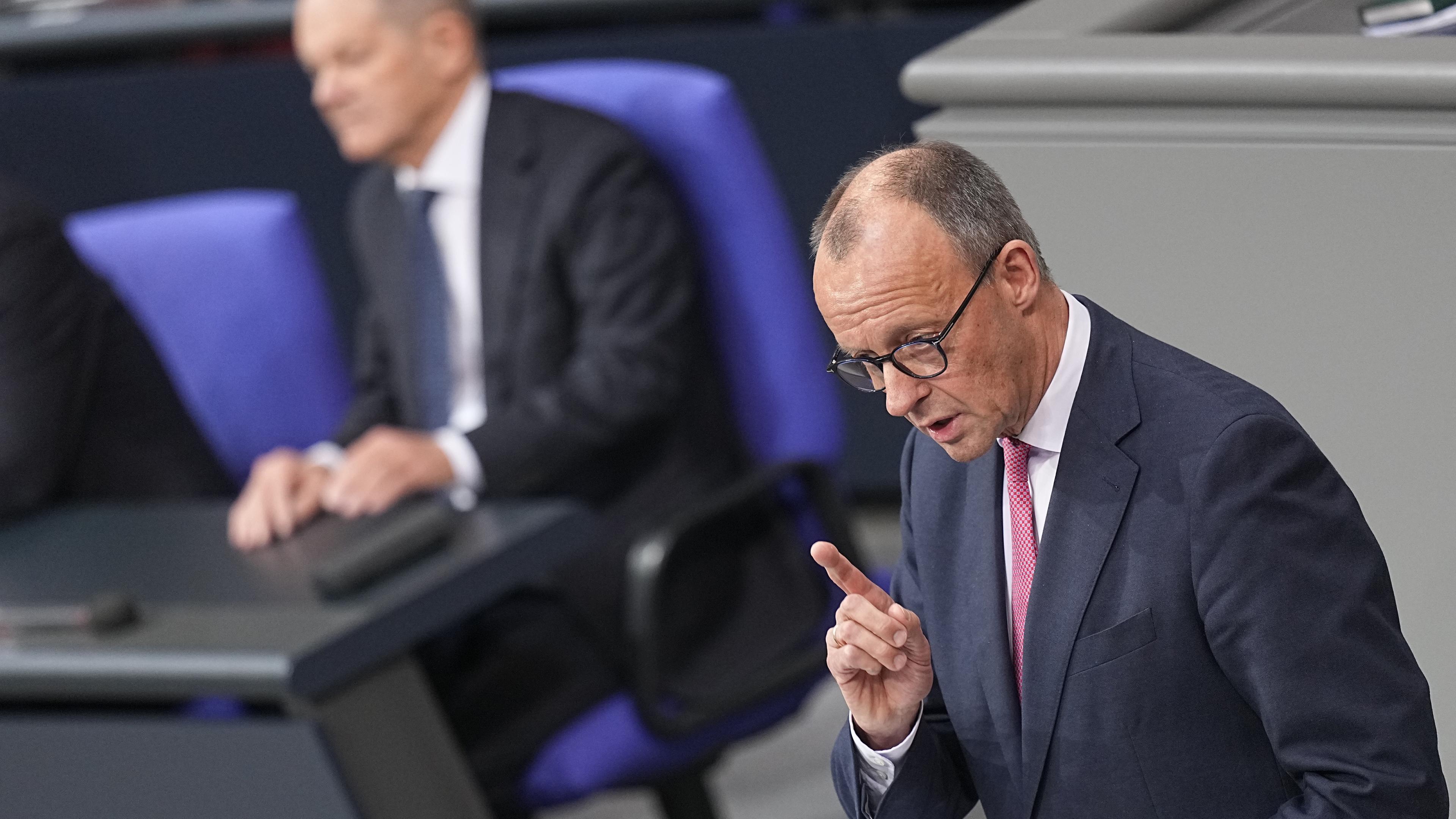 Bundeskanzler Olaf Scholz (SPD) hört Friedrich Merz (r.), CDU-Bundesvorsitzender und CDU/CSU-Fraktionsvorsitzender im Bundestag, zu.