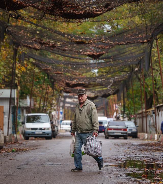 Ein Mann überquert in Cherson eine Straße, die mit gespannten Anti-Drohnen-Netzen geschützt ist, während einer humanitären Hilfsmission für den Ort Oleschky .