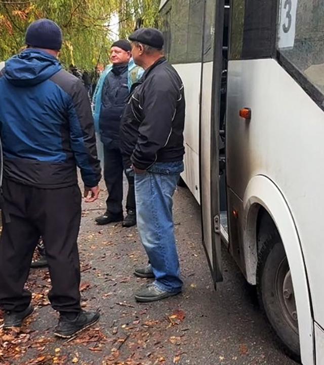 Menschen stehen am 30.10.2026 in Oleschky, Ukraine, an einem Bus.