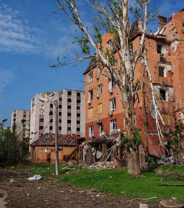 Ein Journalist geht in Oleschky vor einem Wohngebäude entlang, das bei einem russischen Angriff beschädigt wurde – während einer lokalen Waffenruhe im Zusammenhang mit einer humanitären Hilfsaktion.