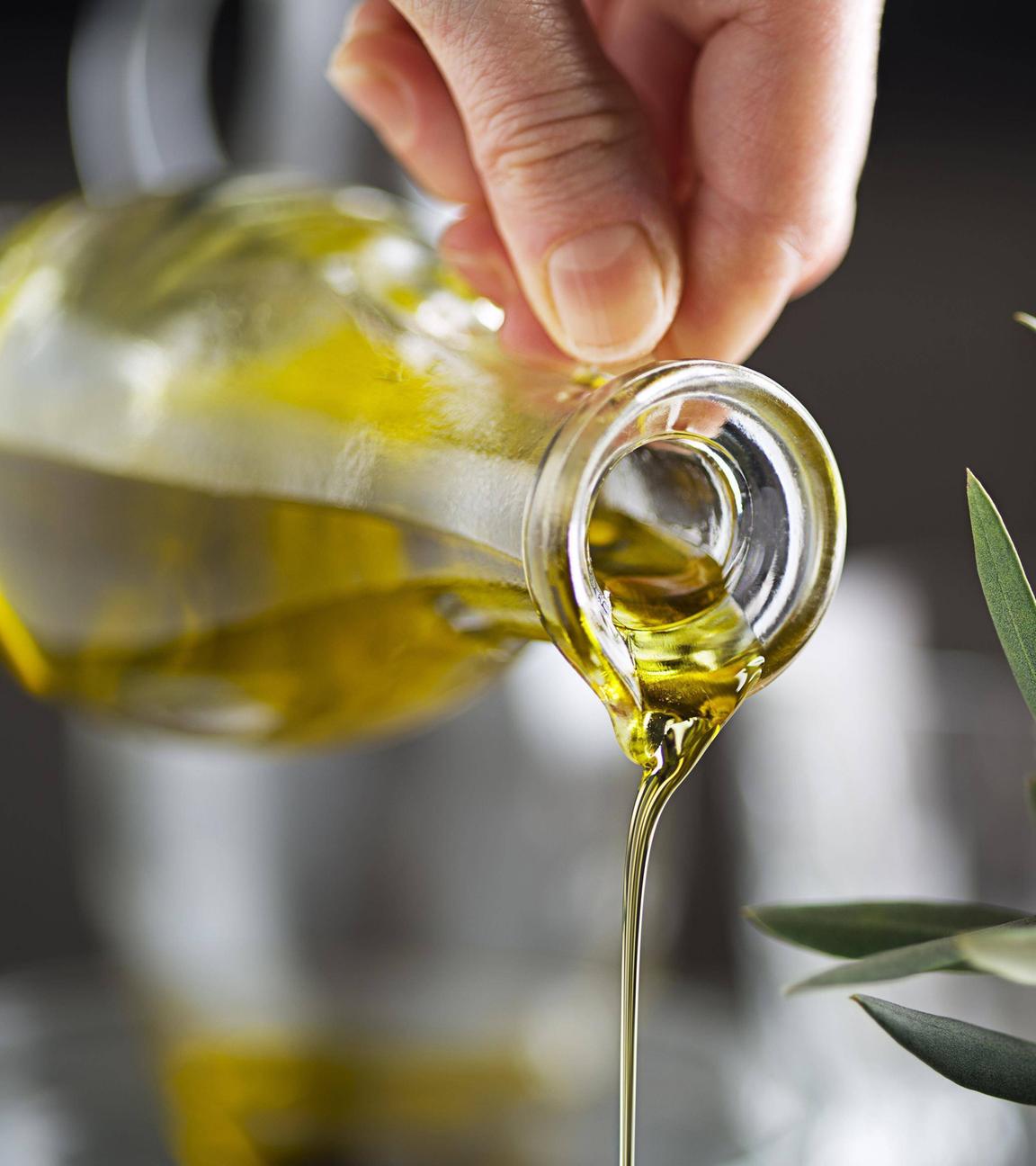 Olivenöl wird aus einer Karaffe gegossen.