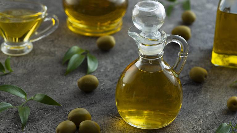 Mit Olivenöl gefüllte Kännchen und Oliven