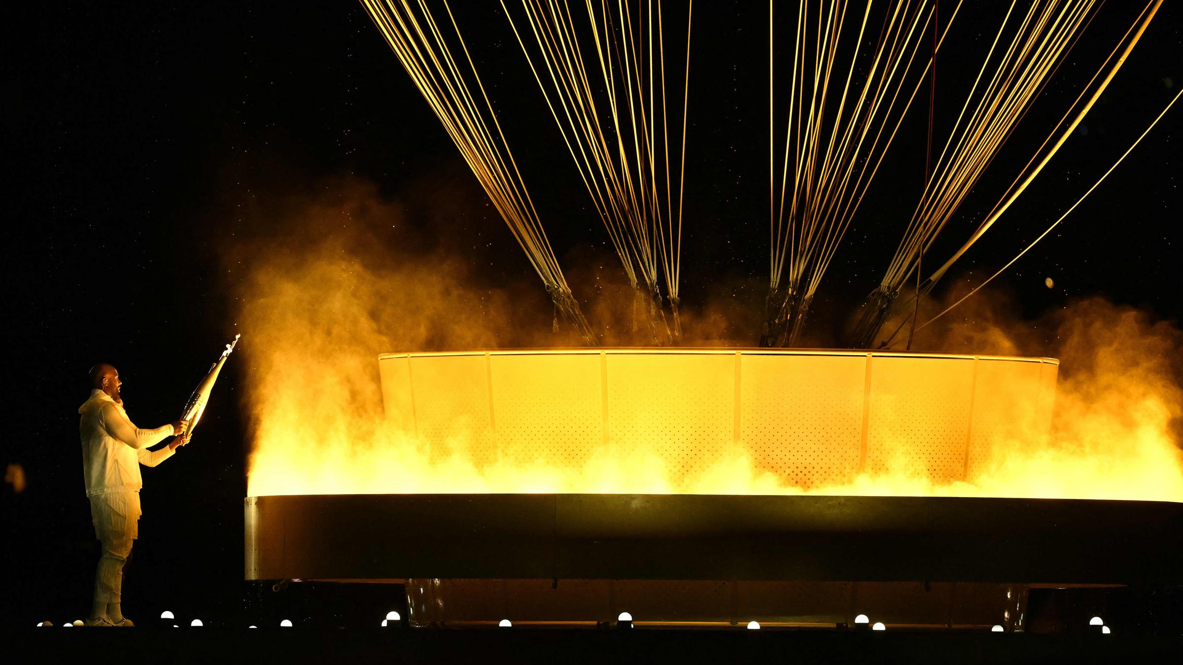 Frankreichs Fackelträger Judoka Teddy Riner und Sprinterin Marie-Jo Perec zünden das olympische Feuer an