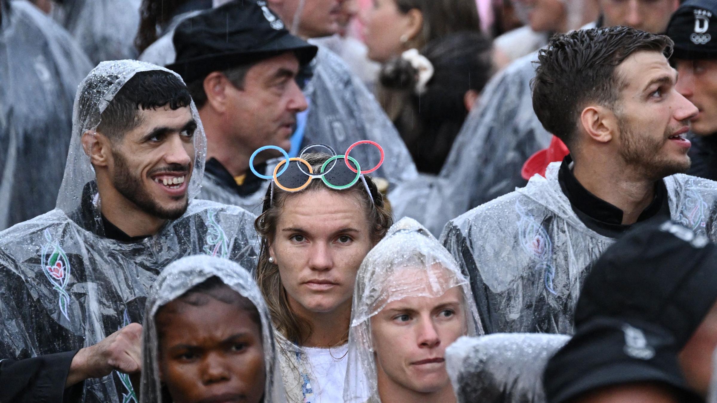 Während der Eröffnungsfeier besteigen deutsche Sportler in Regenponchos ein Boot bei der schwimmenden Parade auf der Seine.